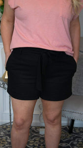 Forever Fierce Front Tie Waist, Linen Paperbag Shorts - Black - Fate & Co. These super cute front tie waist, linen paper bag shorts are so IN right now!! Featuring an elastic stretch waistband, tie belt and side pockets, these paperboy shorts can be dressed up or worn casually depending on the occasion! Tuck in a more fitted top and wedges for a more "going out" look or front tuck a tee and slide on a pair of flip flops for a more casual day look! 