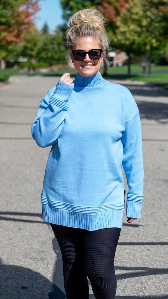 Ultra soft knitted fabric shapes this super buttery sweater that features a mock neckline, one buttoned shoulder, long sleeves and a relaxed bodice. Ribbed detail accents the neckline, cuffs and hem for added texture to the top. Pair with your favorite denim or leggings and booties for a perfect cozy and comfortable look.  Color: Blue 